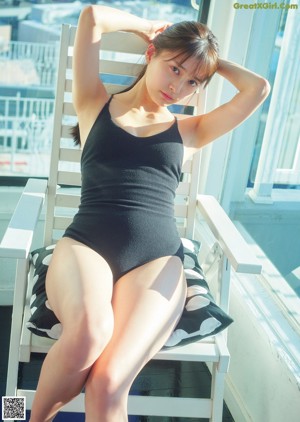 A woman in a black bathing suit sitting on a red couch.