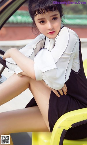 A woman in a black and white dress sitting on a bench.