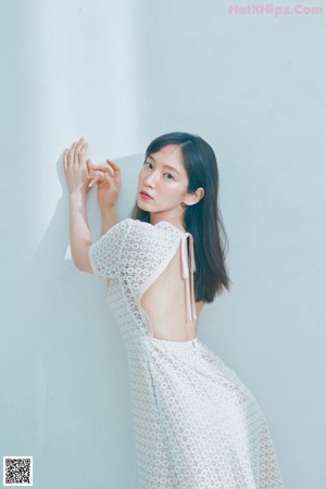 A woman in a white dress is posing for a magazine.