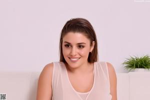A naked woman in a white tank top posing for the camera.