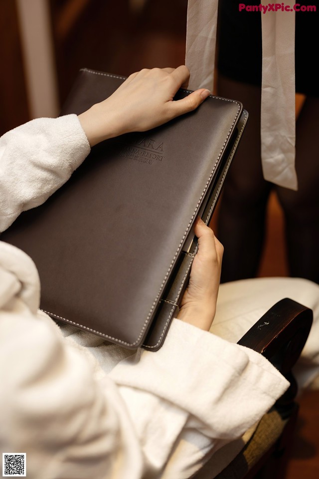 A person holding a brown leather folder in their hands.