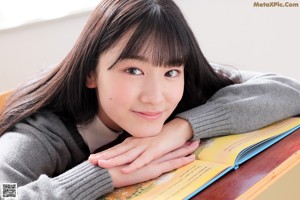 A young woman sitting on a window sill wearing a school uniform.