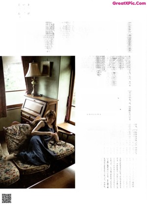 A woman with long brown hair sitting on the floor.