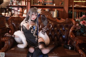 A woman in a black dress sitting on a chair holding a knife.