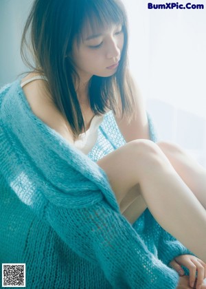 A woman sitting on the floor in a sheer blue dress.