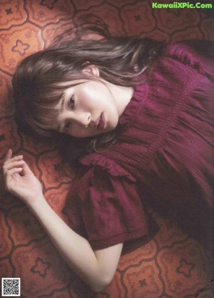 A woman laying on top of a bed next to a window.
