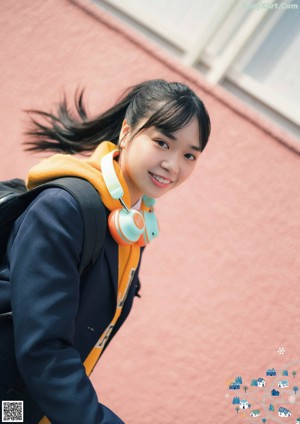 A young woman wearing headphones crouching down on the street.