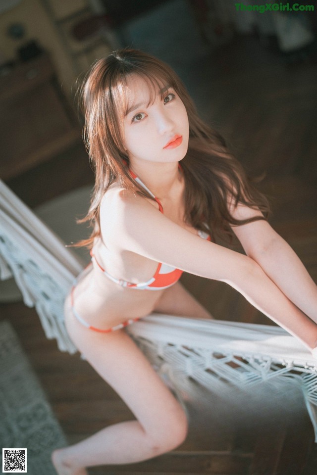 A woman in a bikini sitting on a hammock.