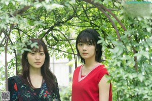 Two young women standing next to each other in front of a window.