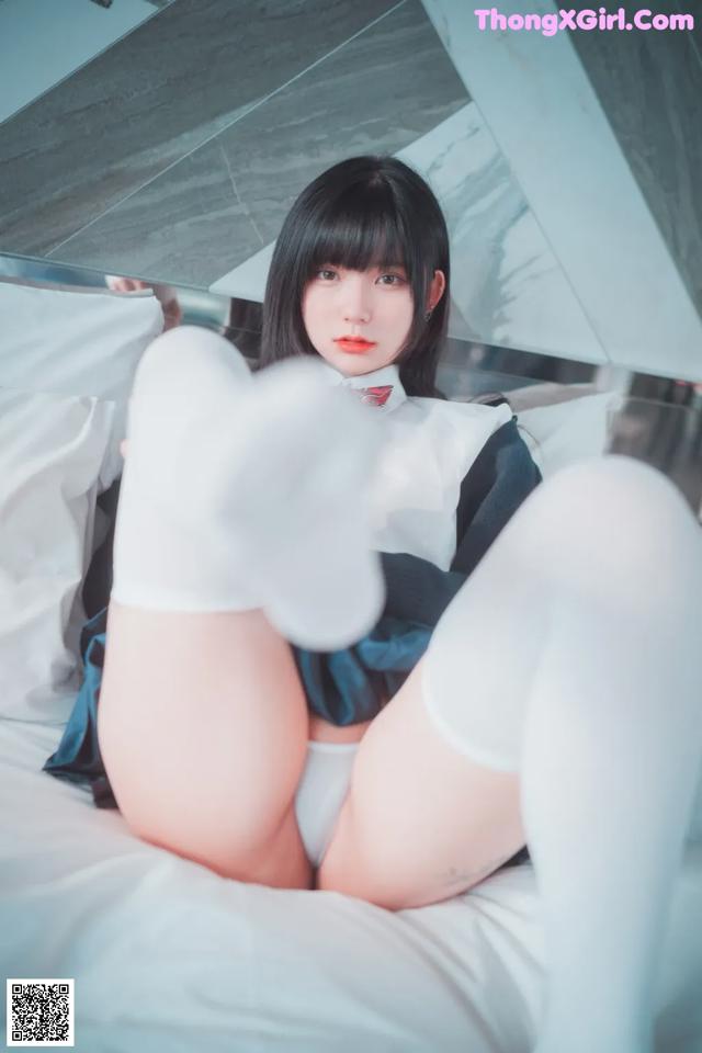 A woman in white stockings is sitting on a bed.
